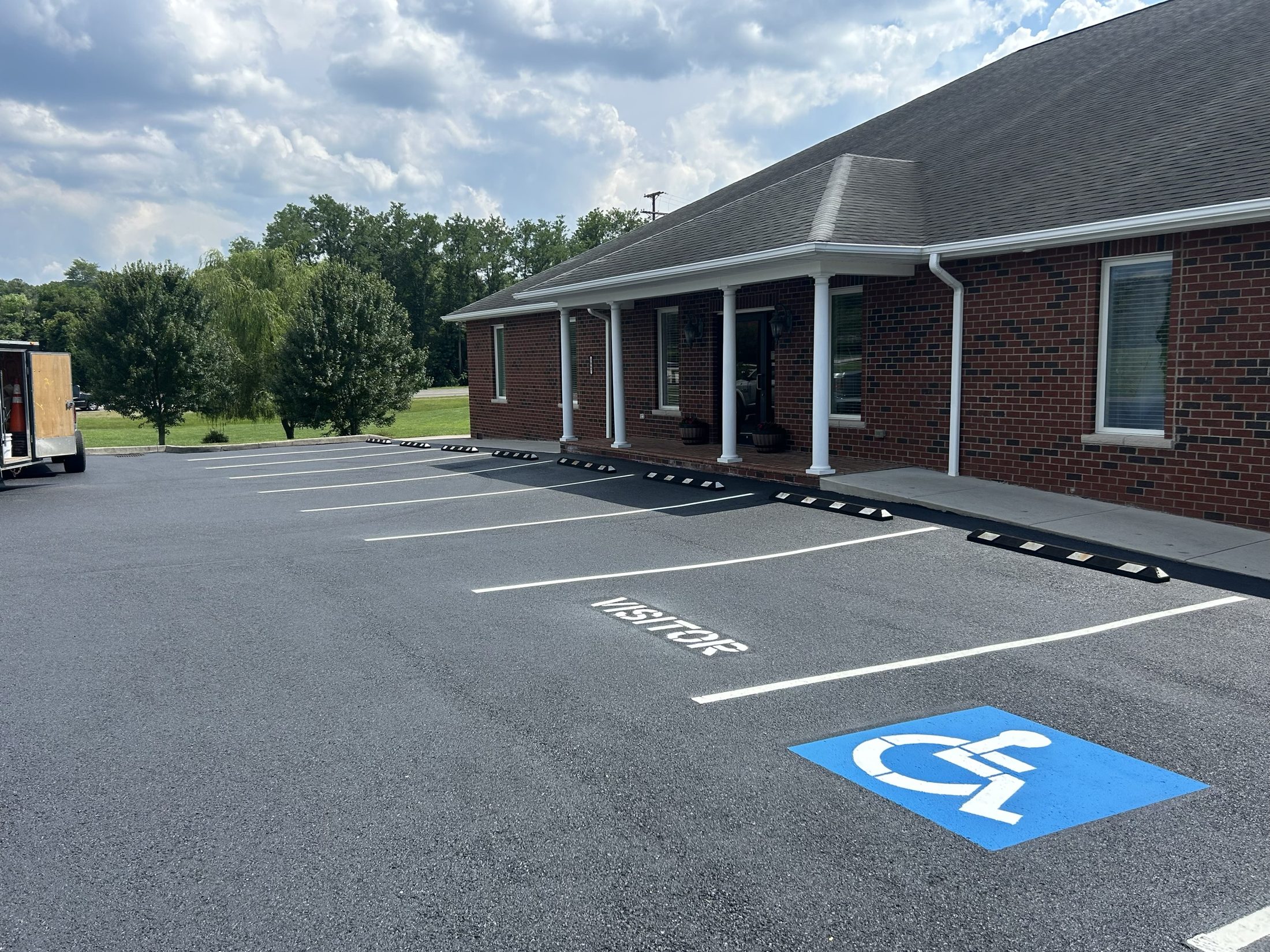 ADA stall, VISITOR stencil and striped curb at a commercial office lot